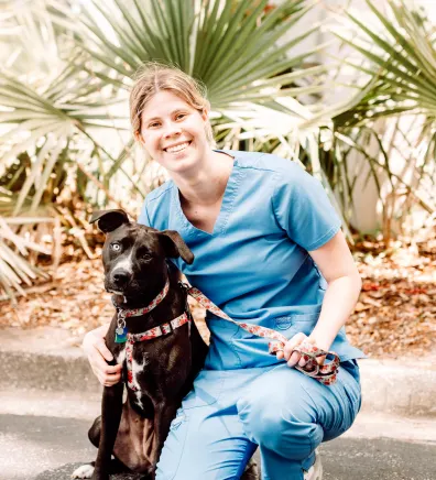 A staff member posing with a black dog 